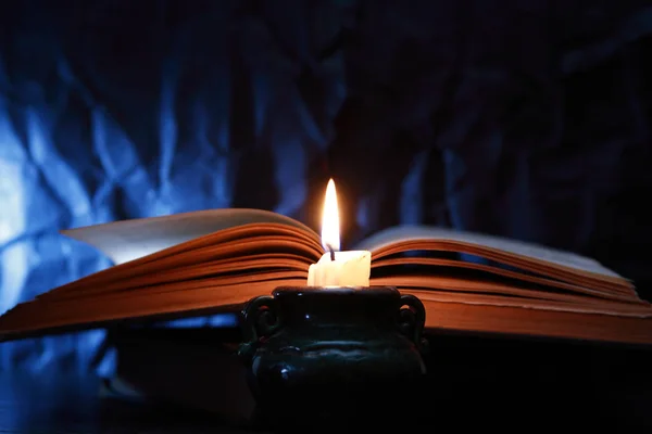 Stillleben Mit Brennender Kerze Neben Altem Buch Auf Dunkelblauem Hintergrund — Stockfoto