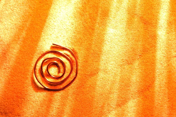 Abstraktes Spiralsymbol Aus Kupferdraht Auf Sandoberfläche lizenzfreie Stockbilder