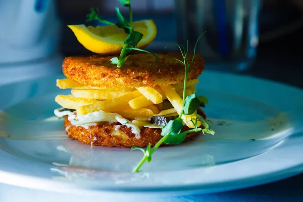 limon parçası et hamburger kızarmış patates ve salatalık turşusu ile dekore edilmiş