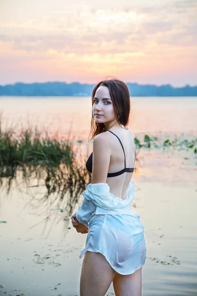 ランジェリーと白いシャツの魅力的な女の子は 夜明けに川に立っています ファッション ポートレート — ストック写真