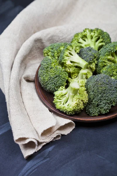 Brócoli orgánico verde fresco en placa marrón y servilleta de lino —  Fotos de Stock