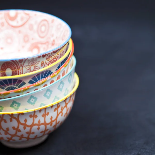 Stack of colorful empty ceramic bowls closeup on black board bac — Stock Photo, Image