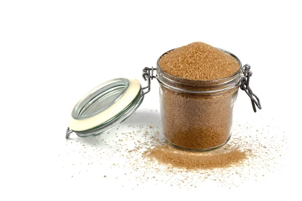 Brown cane sugar in glass jar isolated on white background. — Stock Photo, Image