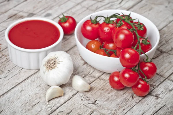 Fresh tomatoes in white bowl, sauce and raw garlic on rustic woo — Stock Photo, Image