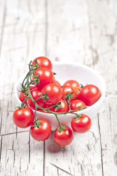 Fresh tomatoes in white bowl on rustic wooden table. — Stock Photo, Image