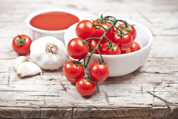 Fresh tomatoes in white bowl, sauce and raw garlic on rustic woo — Stock Photo, Image