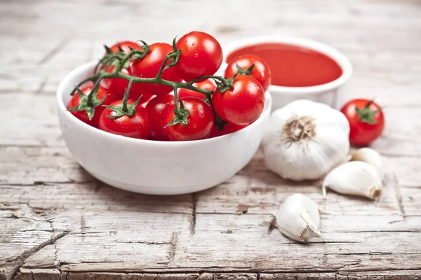 Fresh tomatoes in white bowl, sauce and raw garlic on rustic woo — Stock Photo, Image