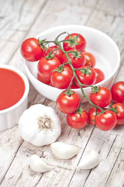 Fresh tomatoes in white bowl, sauce and raw garlic on rustic woo — Stock Photo, Image