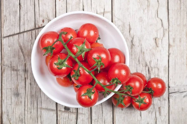 Verse tomaten in witte kom op rustieke houten tafel. — Stockfoto