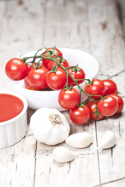 Fresh tomatoes in white bowl, sauce and raw garlic on rustic woo — Stock Photo, Image