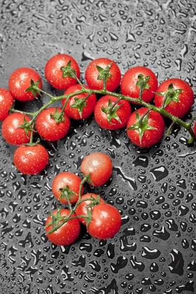 Tomates cereja úmidos orgânicos frescos cacho closeup em preto — Fotografia de Stock