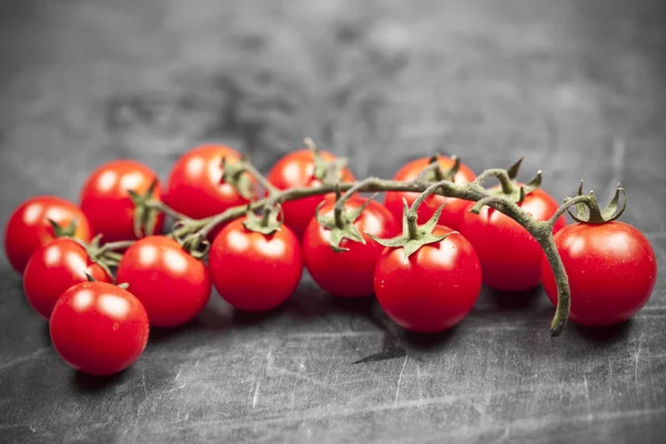 Fresh organic cherry tomatoes bunch closeup on black board. — Stock Photo, Image