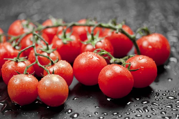 Verse natte biologische cherry tomaten stelletje close-up op zwart. — Stockfoto