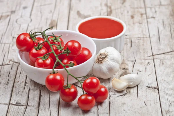 Fresh tomatoes in white bowl, sauce and raw garlic on rustic woo — Stock Photo, Image