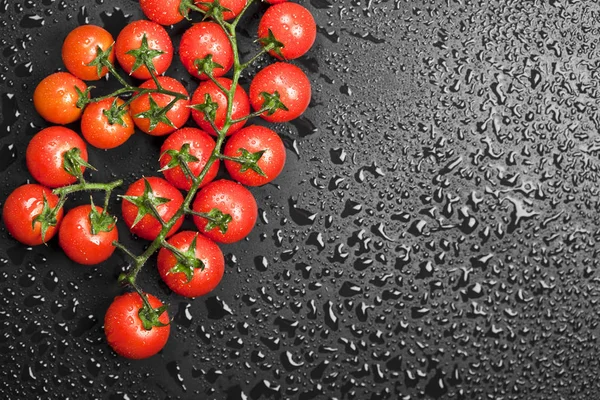 Tomates cereja orgânicos frescos bando closeup em preto molhado backgro — Fotografia de Stock