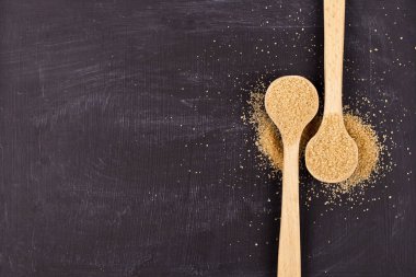 Siyah arka plan üzerinde iki tahta kaşık kahverengi baston şeker.