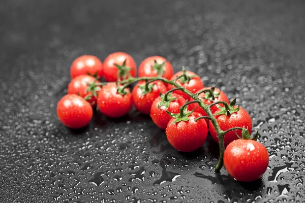 Tomates cereja orgânicos frescos bando closeup em preto . — Fotografia de Stock