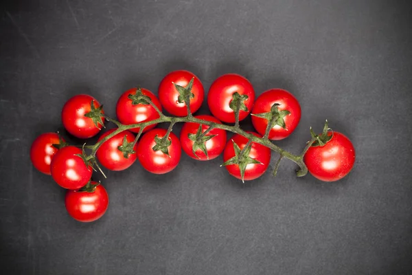 Tomates cereja orgânicos frescos bando closeup em backg placa preta — Fotografia de Stock