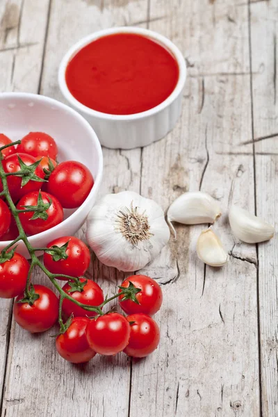 Fresh tomatoes in white bowl, sauce and raw garlic on rustic woo — Stock Photo, Image