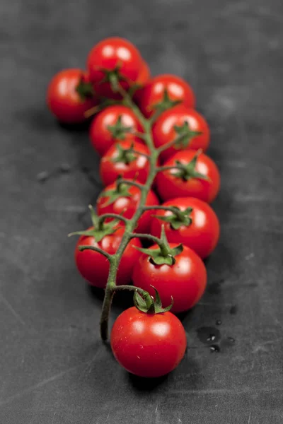 Tomates cereja orgânicos frescos bando closeup na placa preta . — Fotografia de Stock
