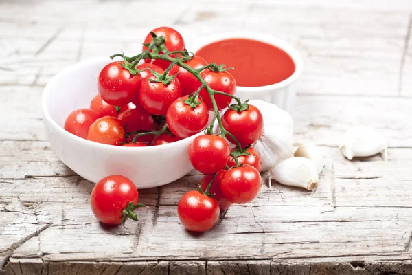 Tomates frescos em tigela branca, molho e alho cru no woo rústico — Fotografia de Stock