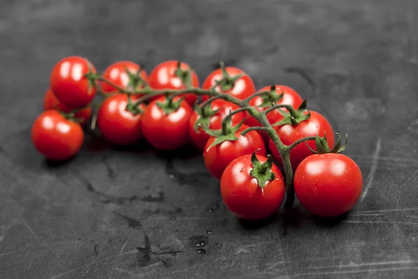 Manojo de tomates cherry orgánicos frescos primer plano en la pizarra negra . —  Fotos de Stock
