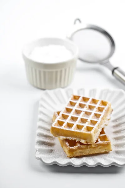 Belgium waffers with sugar powder on ceramic plate and strainer — Stock Photo, Image