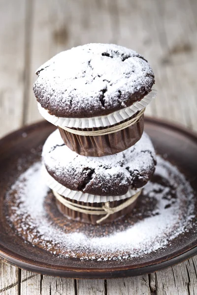 Muffins escuros de chocolate com açúcar em pó na placa marrom em rusti — Fotografia de Stock