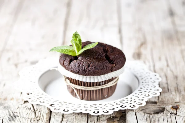 Свежий темный шоколадный кекс с мятными листьями на белой тарелке — стоковое фото