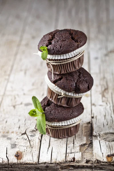 Três muffins de chocolate escuro frescos com folhas de hortelã . — Fotografia de Stock