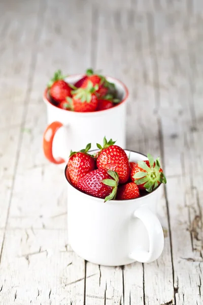Organiska röda jordgubbar i två vita keramiska koppar på rustik Woo — Stockfoto