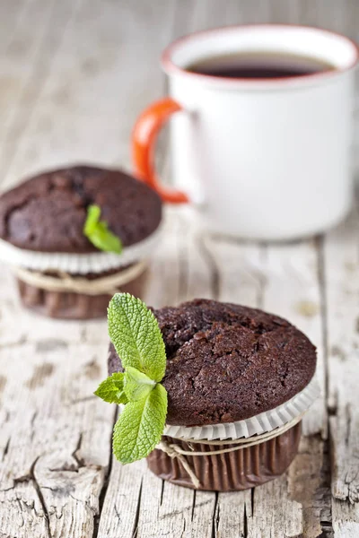 Fresh dark chocolate muffins with mint leaves and cup of tea on — Stock Photo, Image