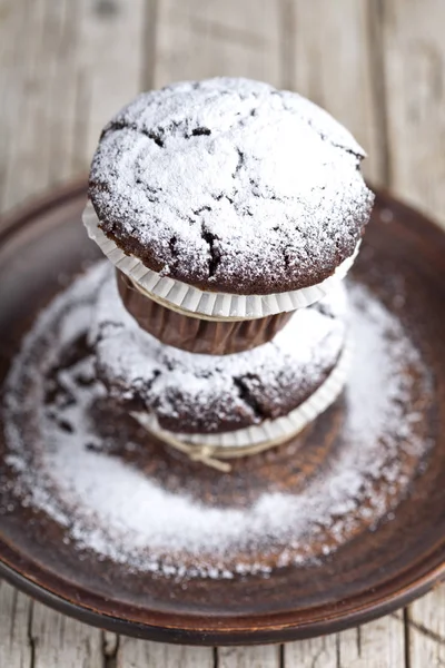 Muffins de chocolate escuro com açúcar em pó na placa marrom em rusti — Fotografia de Stock