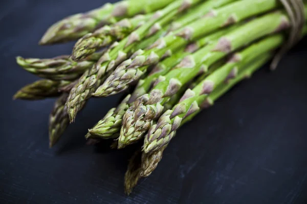 Mazzo di asparagi da giardino crudi freschi primo piano sul retro della lavagna nera — Foto Stock