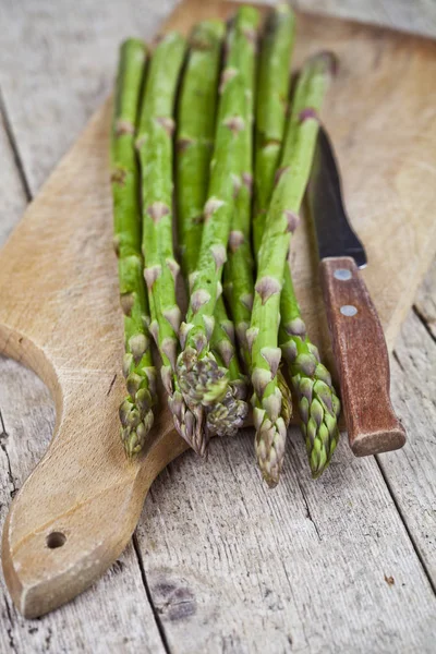 Asparagi da giardino crudi freschi e primo piano coltello sul tagliere su — Foto Stock