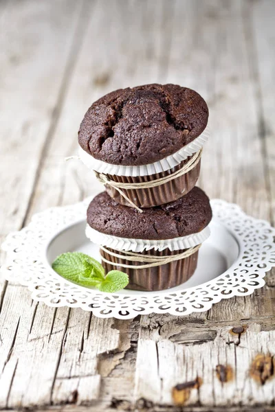 Dvě čerstvé tmavé muffiny s mátovou listou na bílém talíři — Stock fotografie