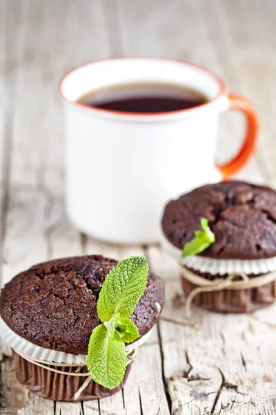 Fresh dark chocolate muffins with mint leaves and cup of tea on — Stock Photo, Image