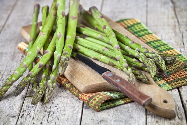 Asparagi da giardino crudi freschi e primo piano coltello sul tagliere su — Foto Stock