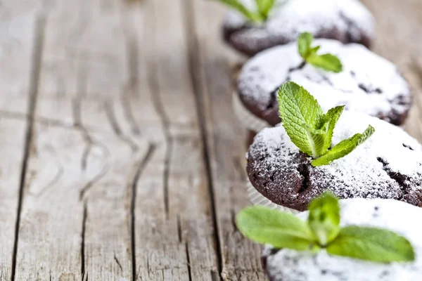 Fresh chocolate dark muffins with sugar powder and mint leaf on — Stock Photo, Image