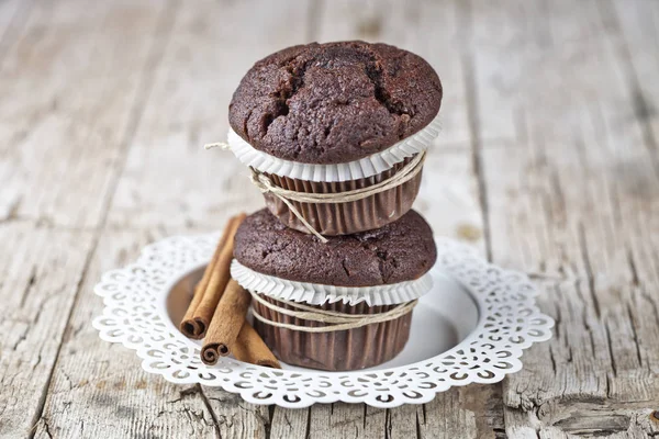Muffins de chocolate escuro fresco com paus de canela na placa branca — Fotografia de Stock
