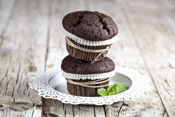 Zwei frische dunkle Schokoladenmuffins mit Minzblättern auf weißem Teller — Stockfoto