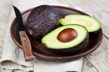 Seramik tabakta taze organik avokado ve keten napki üzerine bıçak