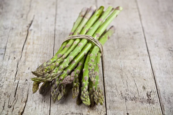 Bund frischer roher Gartenspargel auf rustikalem Holztisch — Stockfoto