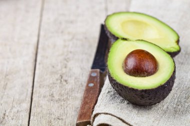 Keten peçete eski ahşap masa arka plan üzerinde avokado ve bıçak. F
