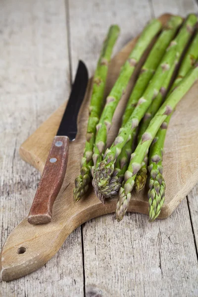 Asparagi da giardino crudi freschi e primo piano coltello sul tagliere su — Foto Stock