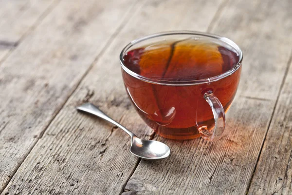Cup of fresh tea and vintage spoon on rustic wooden table backgr — Stock Photo, Image