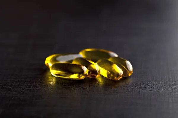 Cápsulas de óleo Omega-3 e vitamina para cuidados de saúde em placa preta — Fotografia de Stock