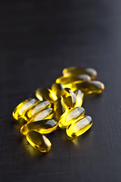 Omega-3 yağ kapsülleri ve vitamin siyah tahta üzerinde sağlık için — Stok fotoğraf