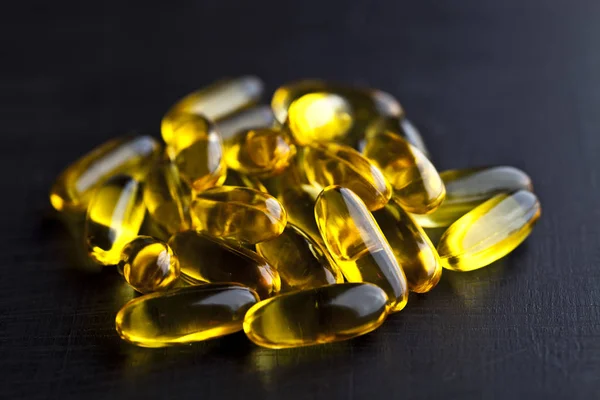 Cápsulas de aceite Omega-3 y vitaminas para el cuidado de la salud en pizarra negra — Foto de Stock