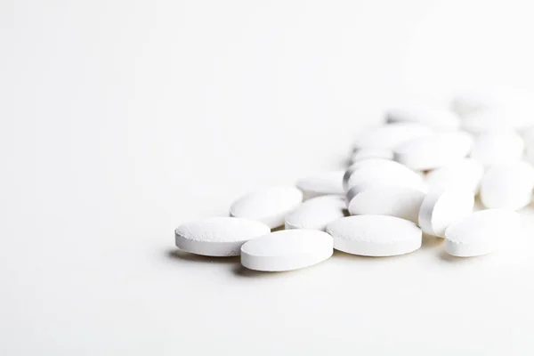 Mucchio di pillole di droga bianche che posano su sfondo bianco . — Foto Stock